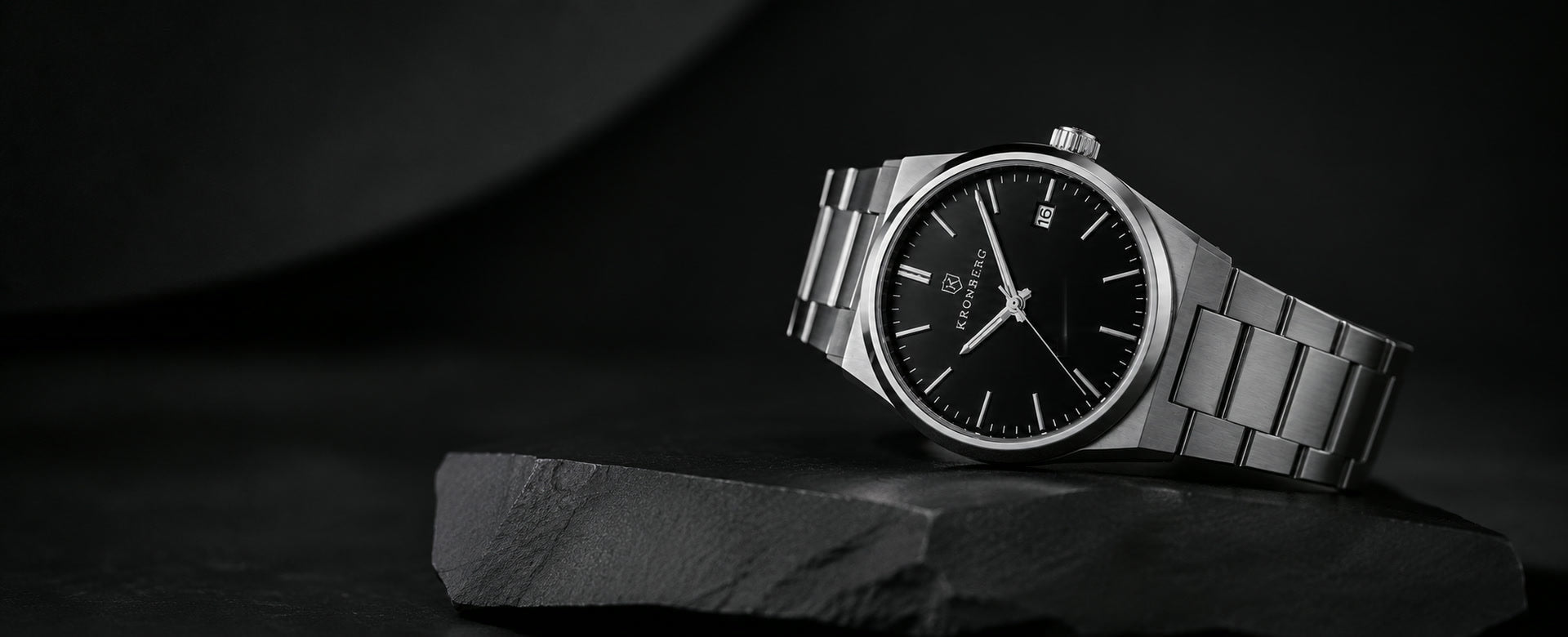 The Kronberg Classic resting on a slate slab, steel case and black dial lit from the side.